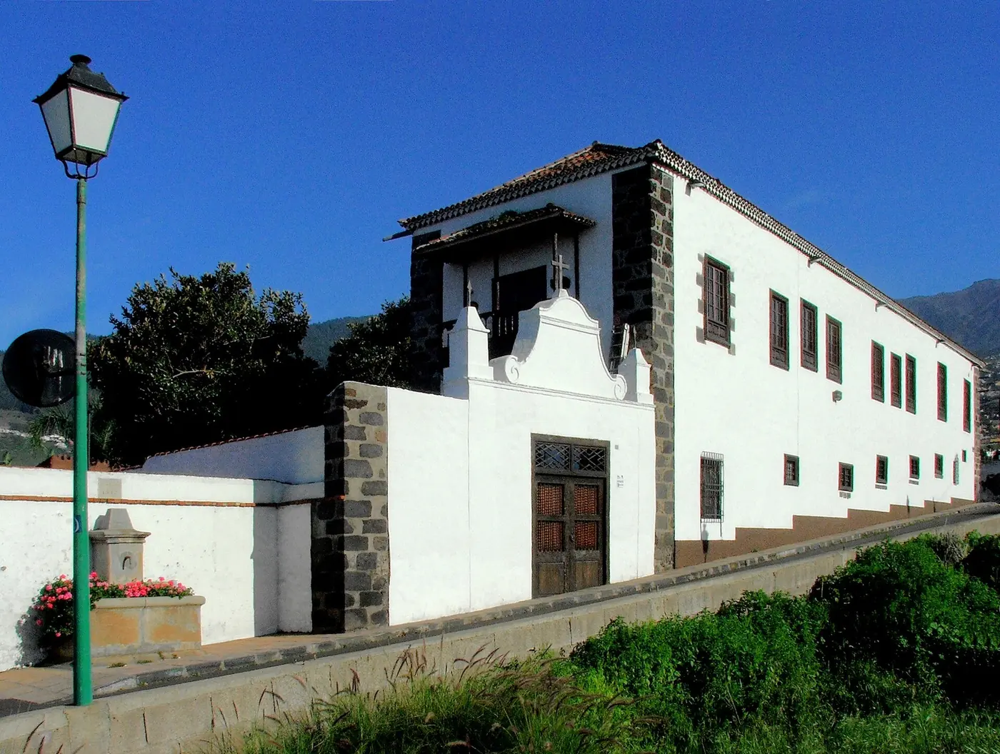 The gable and wooden door of Casa Ábaco's entrance wall, with a wooden balcony above and green mountains behind